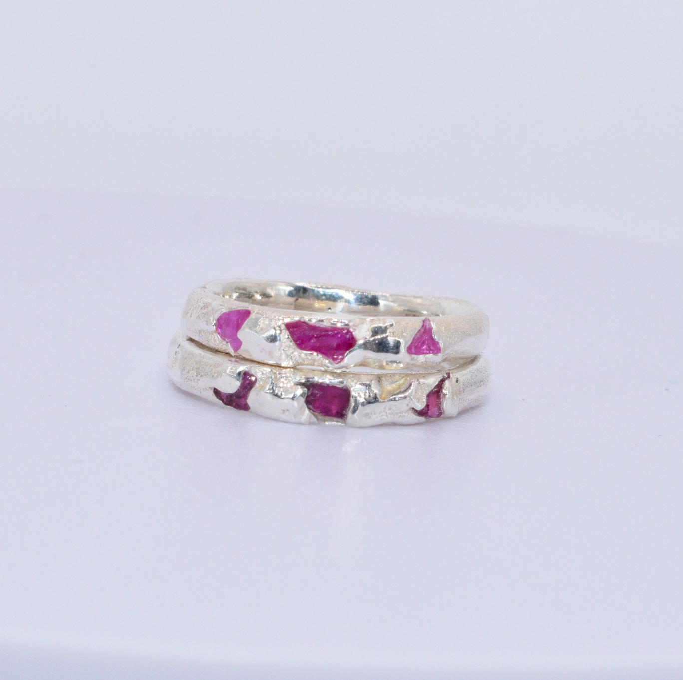 A sterling silver ring with a textured surface featuring shards of ruby, stacked in a narrow band design.