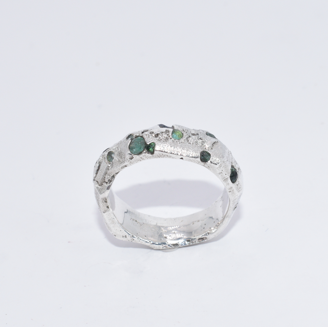 A silver ring with small emerald and synthetic sapphire stones set around its circumference.
