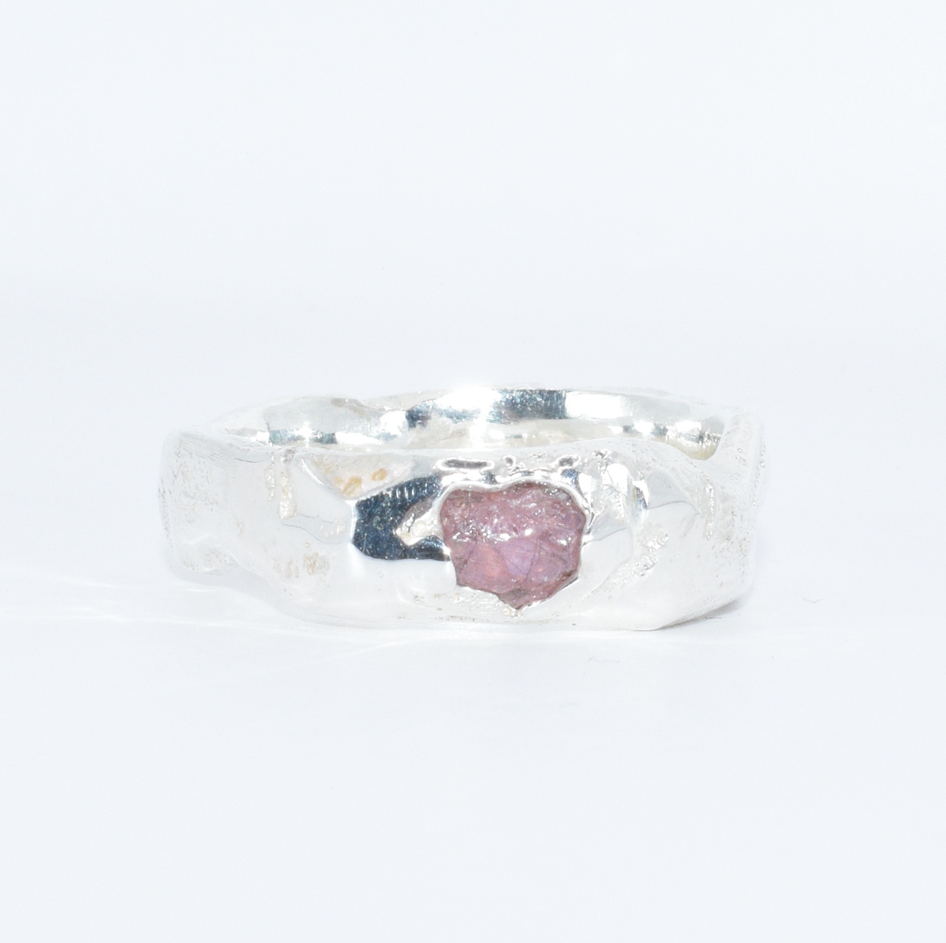 silver ring with uncut pink sapphire set into the front, close up shot